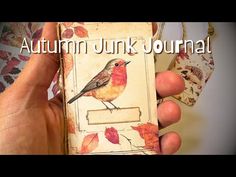 a hand holding an open book with a bird on it and the words autumn junk journal