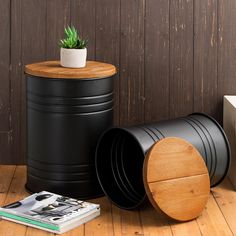 a black trash can sitting on top of a wooden floor next to a potted plant