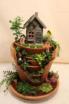 a potted planter filled with plants and miniature figurines sitting on top of it