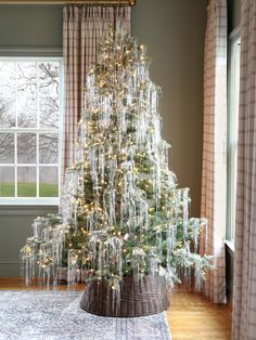 a christmas tree with icicles on it in front of a window and curtained drapes