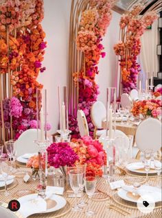 the table is set with white and gold plates, silverware, and pink flowers