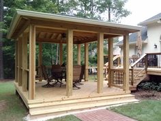 a wooden gazebo sitting on top of a lush green field