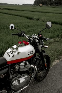 the motorcycle is parked on the side of the road in front of some tall grass