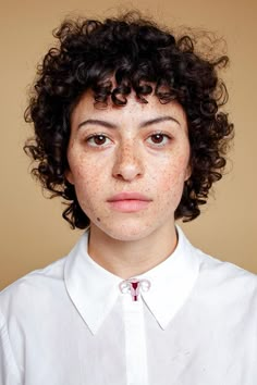 a woman with freckles on her face is looking at the camera while wearing a white shirt