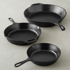 three black cast iron skillets sitting on a table