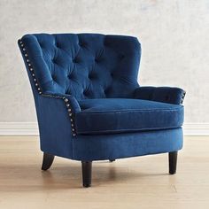 a blue chair sitting on top of a hard wood floor next to a white wall