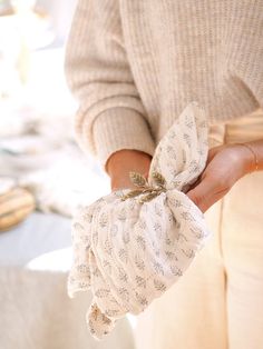 a woman is holding a cloth napkin with a flower on it in her left hand