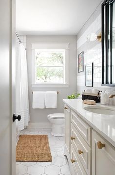 a bathroom with white walls and flooring has a rug on the floor next to the toilet