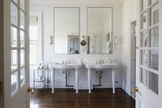 a bathroom with two sinks and mirrors in the wall above them is seen through an open door