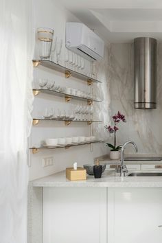 a kitchen with white counter tops and gold accents on the wall, along with stainless steel shelving