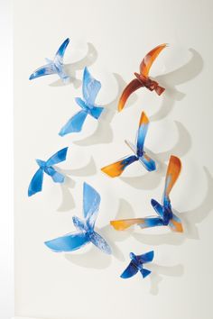 a group of blue and orange paper birds on a white wall