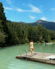 a naked woman is standing on a dock in the middle of a body of water