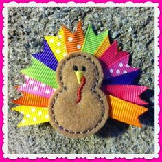 a colorful turkey brooch sitting on top of a stone floor next to a pink frame