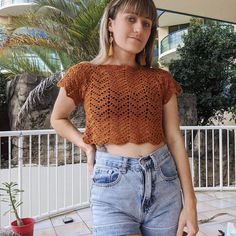 a woman standing in front of a table with food on it and wearing an orange crochet top