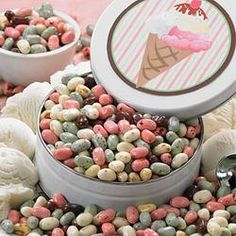 two bowls filled with candy and ice cream on top of a pink table cloth next to other desserts