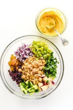 a glass bowl filled with chopped vegetables next to a jar of peanut butter and mustard