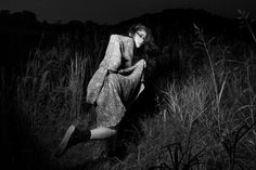 black and white photo of woman in field at night with long hair, wearing an oversize dress