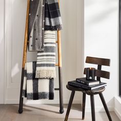 a chair with a blanket on top of it next to a wooden ladder holding books