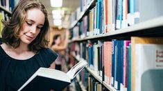 a woman reading a book in a library