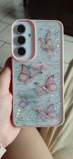 someone is holding up their phone case with butterflies on it and glitters in the back