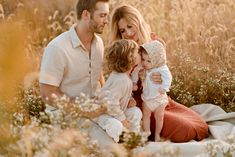 a man and two women are sitting in the grass with their children