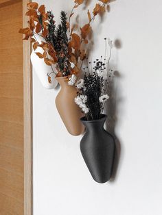 two vases with flowers are hanging on the wall