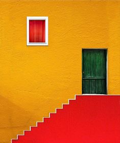 an orange building with a green door and red steps leading up to the top floor