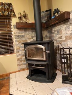 an old fashioned stove is in the corner of a room with tile flooring and stone walls