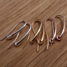 four pairs of silver and gold earrings on a wooden surface, with one earring still attached to the other