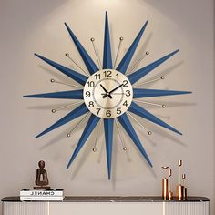 a blue and white clock on the wall above a mantle with books, candles and other items