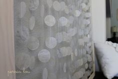 there is a curtain with white circles on it in front of a bed and pillows