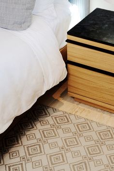 a bed sitting next to a wooden dresser on top of a rug