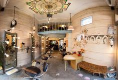 the inside of a hair salon with lots of chairs and mirrors on the wall,