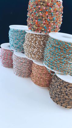 several spools of beaded wire are stacked on top of each other in different colors