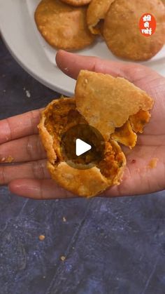 a person is holding some food in their hand and there are cookies on the plate behind them