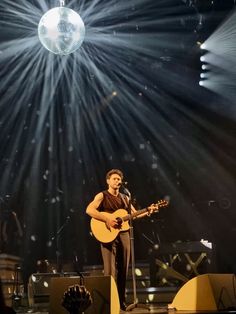 a man standing on top of a stage holding a guitar