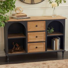 a wooden cabinet with drawers in front of a clock on the wall above it and a potted plant next to it