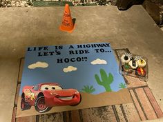 a birthday cake with cars on it and an orange cone in the air next to it