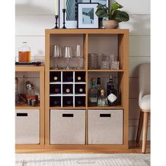 a wooden shelf filled with bottles and glasses on top of a white carpeted floor