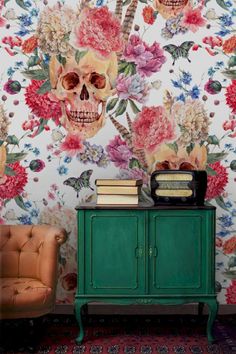 a green cabinet sitting in front of a wall with flowers and skulls painted on it