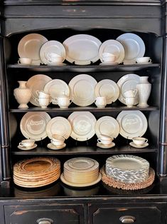 a black china cabinet filled with plates and bowls