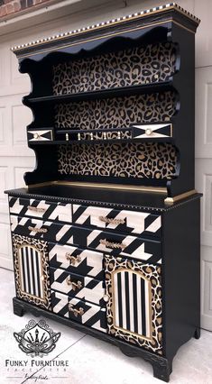 an ornate black and white dresser with leopard print on the top, gold trimmings