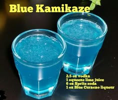 two glasses filled with blue liquid sitting on top of a table