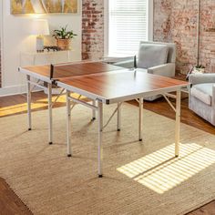 a living room filled with furniture and a ping pong table in front of a window