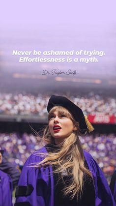 a woman with long hair wearing a graduation cap and gown in front of a stadium