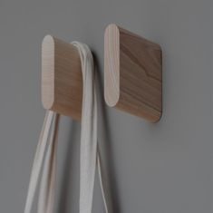 two pieces of wood hang on the wall next to a white bag and another piece of cloth