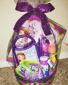 a purple basket filled with lots of toys and candy on top of a carpeted floor