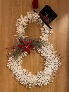 a snowflake wreath on the floor with a book and christmas decorations around it