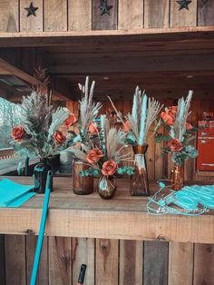 vases filled with flowers sitting on top of a wooden shelf next to other items