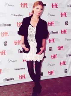 a woman standing in front of a red carpet wearing black and white dress with short sleeves